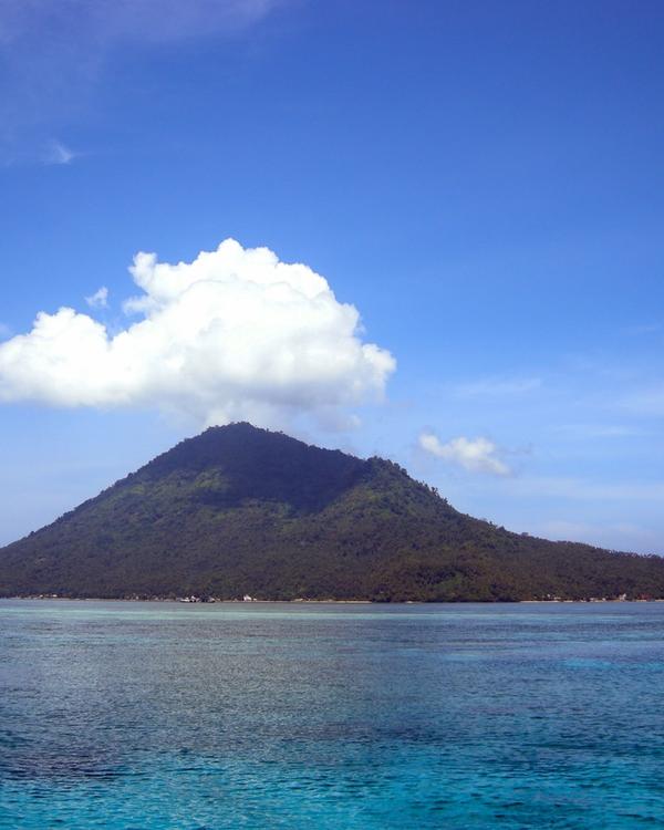 Manado Tua volcano rising above the reef water off Bunaken, North Sulawesi