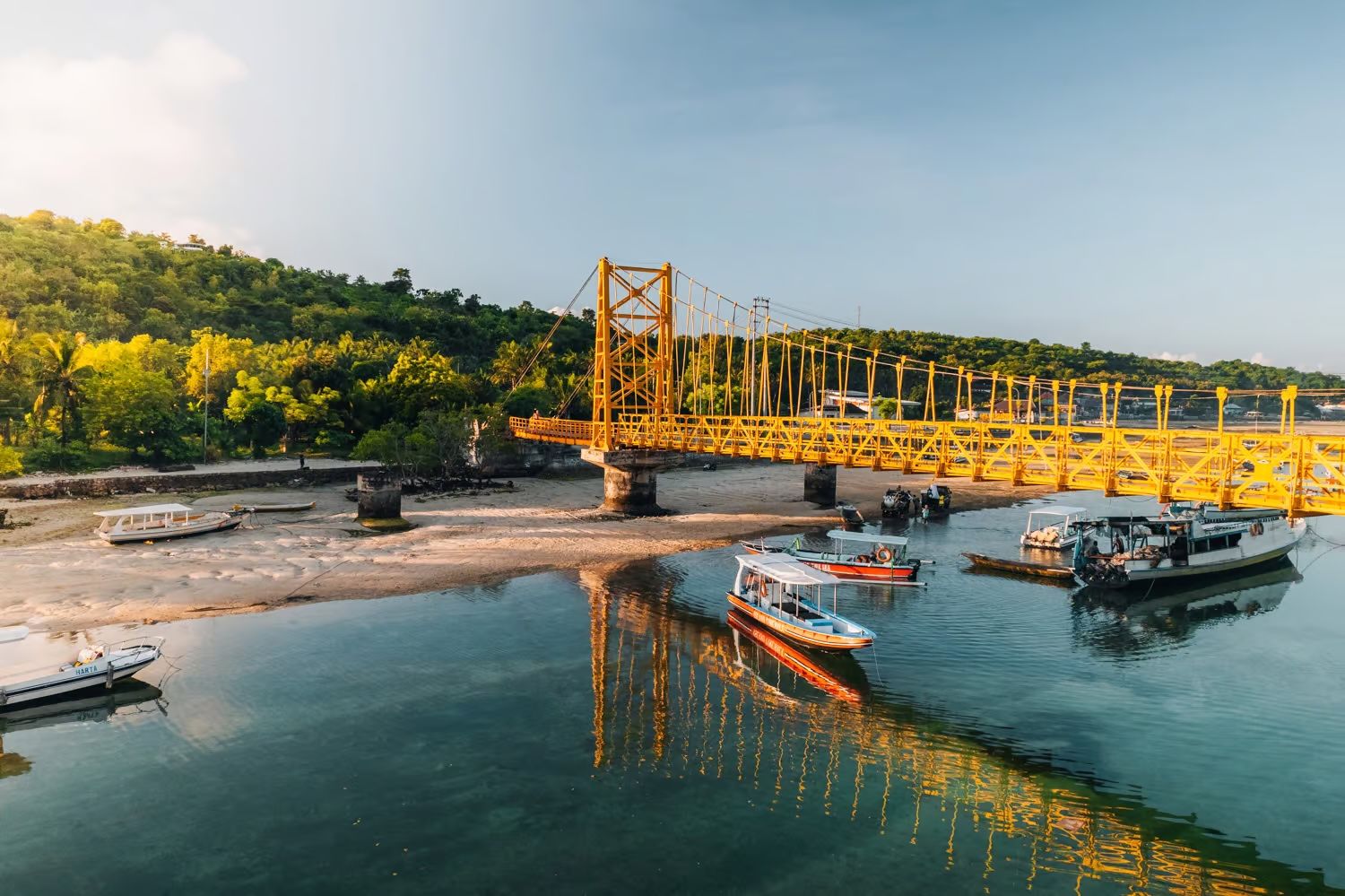The Yellow Bridge linking Nusa Lembongan and Nusa Ceningan at low tide, with boats moored in the channel