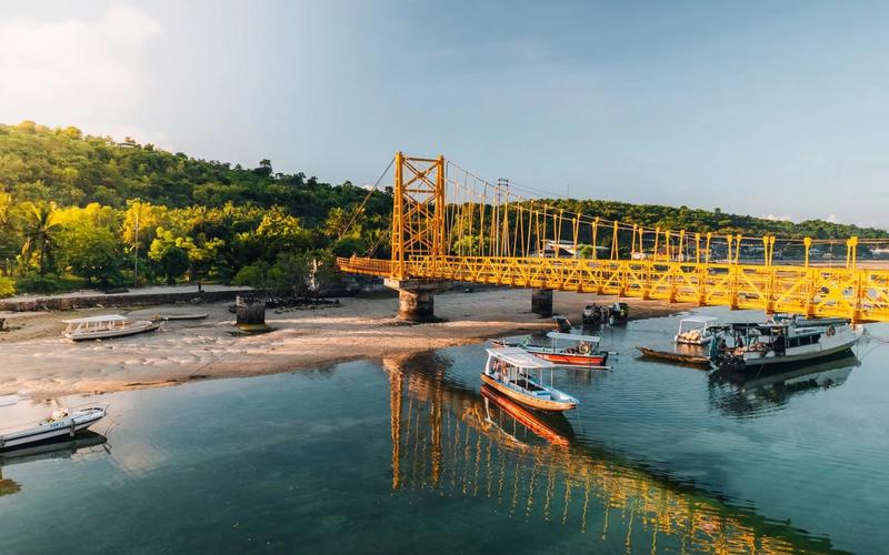 The Yellow Bridge linking Nusa Lembongan and Nusa Ceningan at low tide, with boats moored in the channel