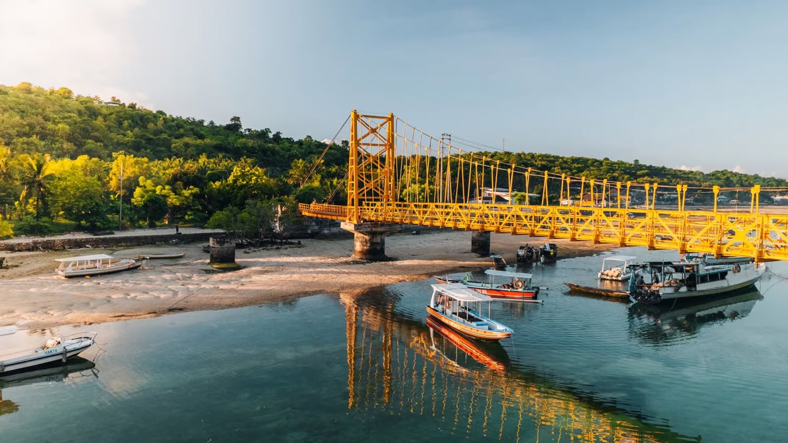 The Yellow Bridge linking Nusa Lembongan and Nusa Ceningan at low tide, with boats moored in the channel