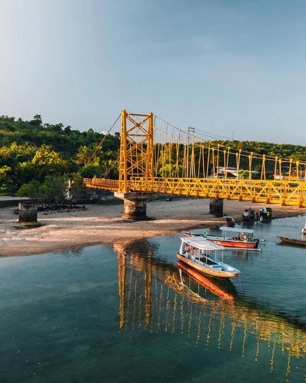 The Yellow Bridge linking Nusa Lembongan and Nusa Ceningan at low tide, with boats moored in the channel