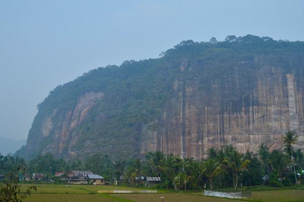 The sheer cliff walls of Harau Valley rising above rice fields and village houses in Lima Puluh Kota, West Sumatra