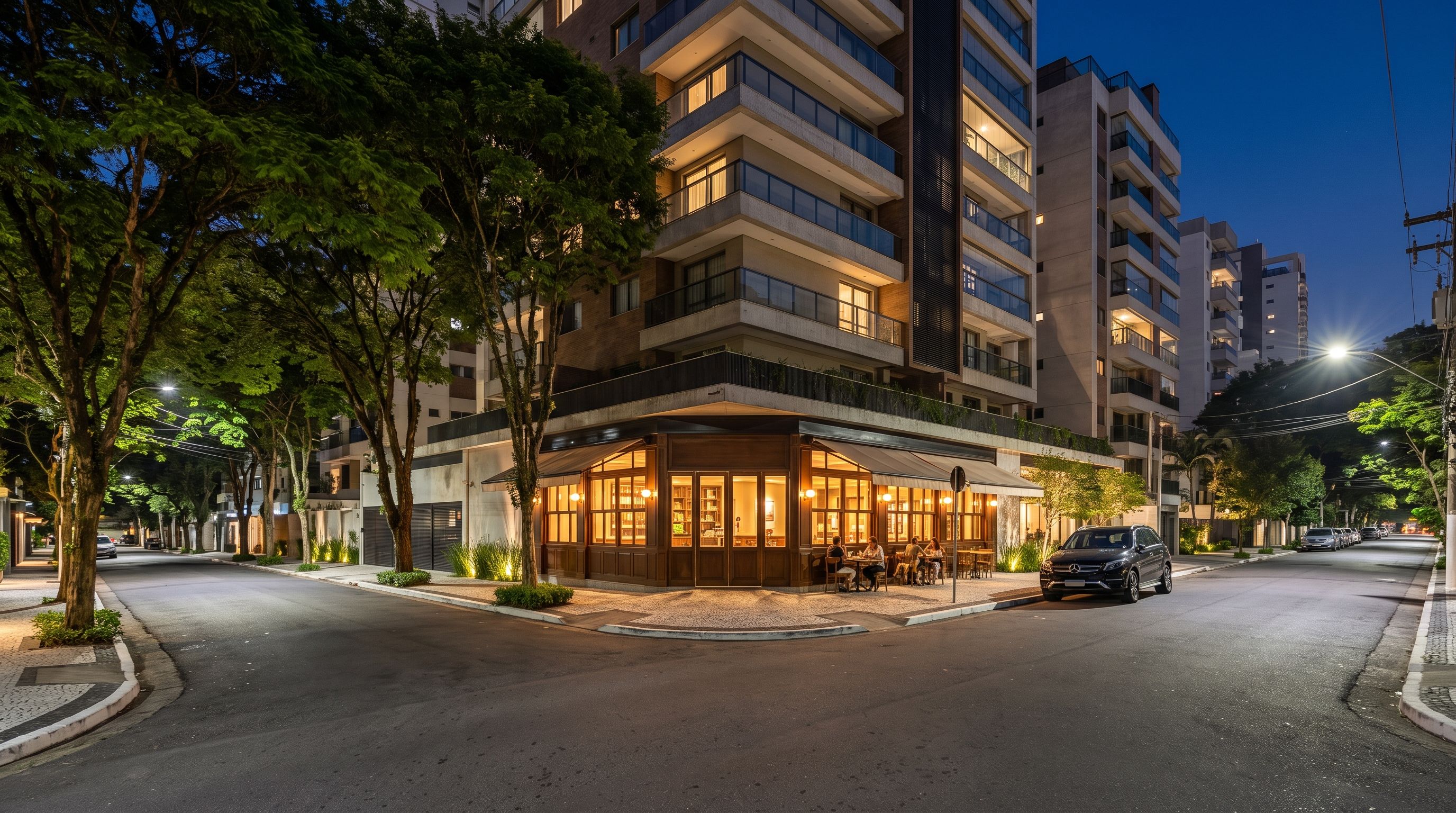 Esquina residencial em Moema ao anoitecer: prédio contemporâneo com varandas iluminadas, café de esquina em madeira, árvores na calçada