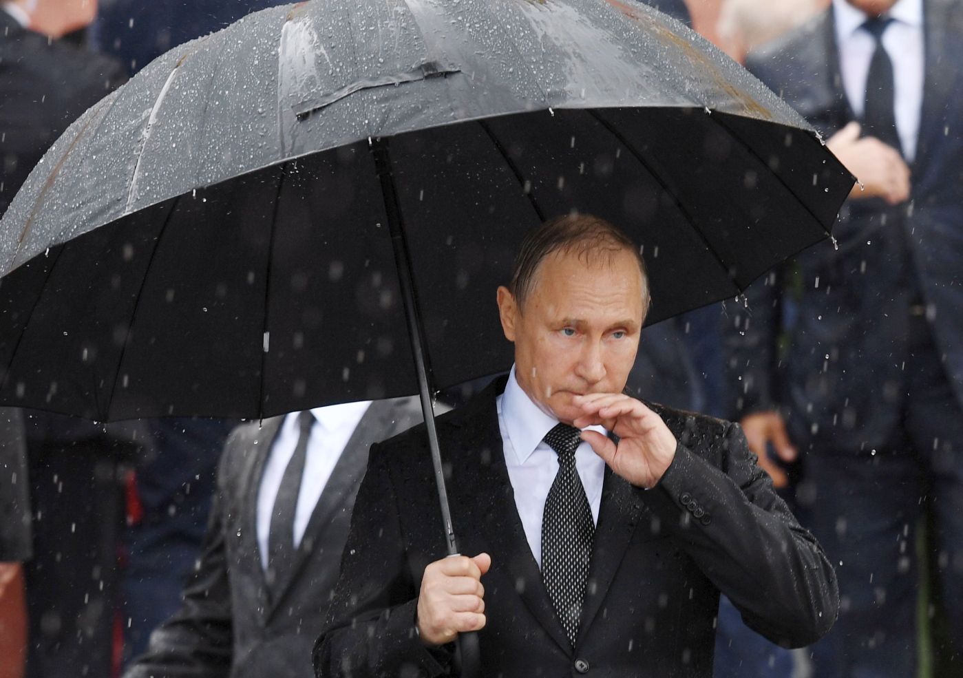 TOPSHOT - Russian President Vladimir Putin holds an umbrella as he attends a ceremony marking the 76th anniversary of the Nazi German invasion, by the Kremlin walls in Moscow on June 22, 2017.  / AFP PHOTO / Natalia KOLESNIKOVA