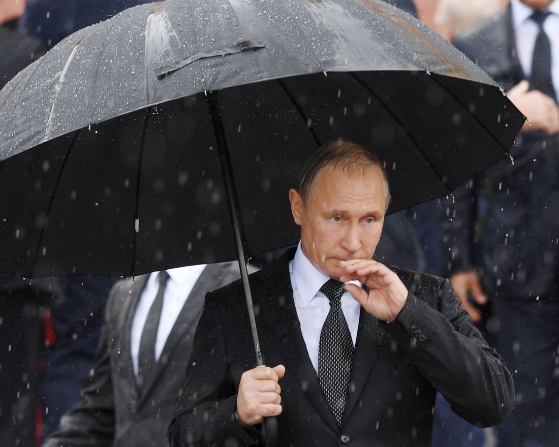 TOPSHOT - Russian President Vladimir Putin holds an umbrella as he attends a ceremony marking the 76th anniversary of the Nazi German invasion, by the Kremlin walls in Moscow on June 22, 2017.  / AFP PHOTO / Natalia KOLESNIKOVA