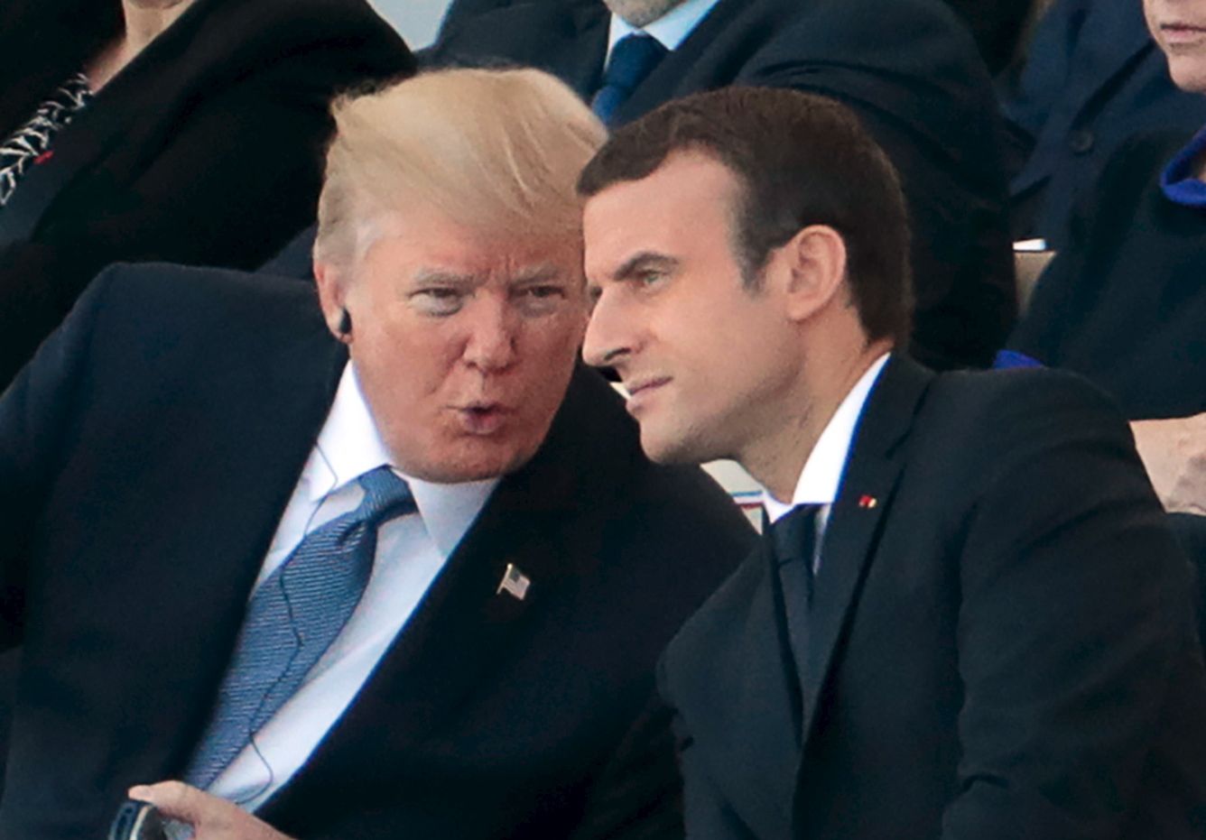 French President Emmanuel Macron (R) listens to US President Donald Trump as they attend the annual Bastille Day military parade on the Champs-Elysees avenue in Paris on July 14, 2017. 
 The parade on Paris's Champs-Elysees will commemorate the centenary of the US entering WWI and will feature horses, helicopters, planes and troops. / AFP PHOTO / joel SAGET