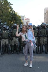 MAKTDEMONSTRASJON: En ung kvinne med et barn på armen viser v-tegnet foran en rad med opprørspoliti i hovedstaden Minsk. Kvinner har fått en fremtredende plass i opprørsbevegelsen, både blant lederskapet og på gatenivå. FOTO: MAXIM SARYCHAU