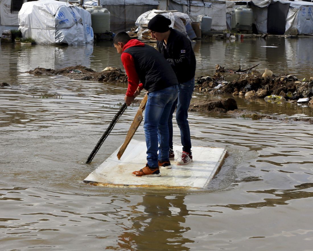 Syrian refugees use a floating piece of wood to move around after heavy rain caused flooding at a refugee camp in the town of Bar Elias, in the Bekaa Valley, Lebanon, Thursday, Jan. 10, 2019. A storm that battered Lebanon for five days has displaced many Syrian refugees after their tents got flooded with water or destroyed by snow. (AP Photo/Bilal Hussein)