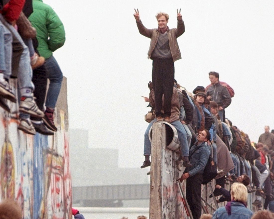 FILE - In this Sunday, Nov. 12, 1989 file photo, Berliners celebrate on top of the wall as East Germans flood through the dismantled Berlin Wall into West Berlin at Potsdamer Platz. When the Berlin Wall fell, the Soviet Union stepped back, letting East Germany's communist government collapse and then quickly accepting German unification. (AP Photo/Lionel Cironneau, File)