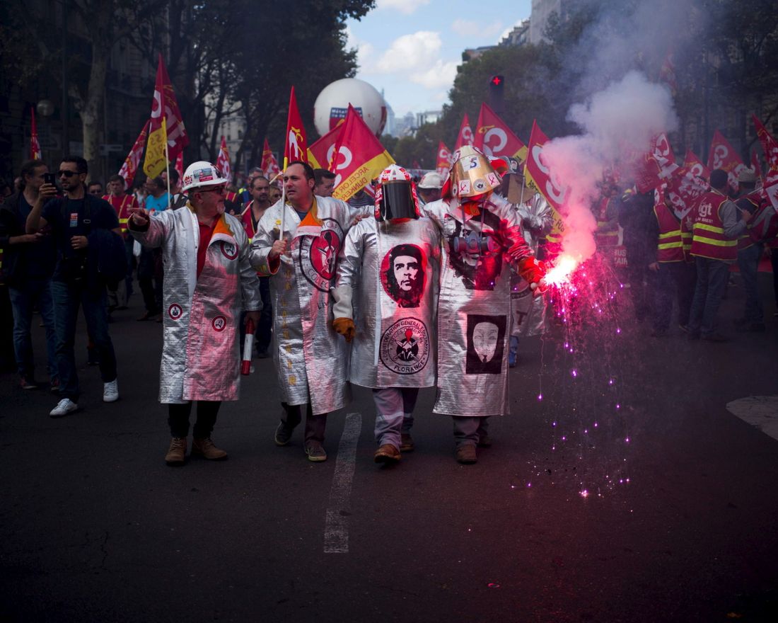 TOPSHOT - Metalworkers demonstrate as they march with flares, banners and flags in the streets of Paris on October 13, 2017. 
 Several thousand workers have taken part in a protest organised by French union CGT for the metallurgy industry in Paris on October 13 to demand a national collective "high level" agreement  for the branch in France. / AFP PHOTO / MARTIN BUREAU