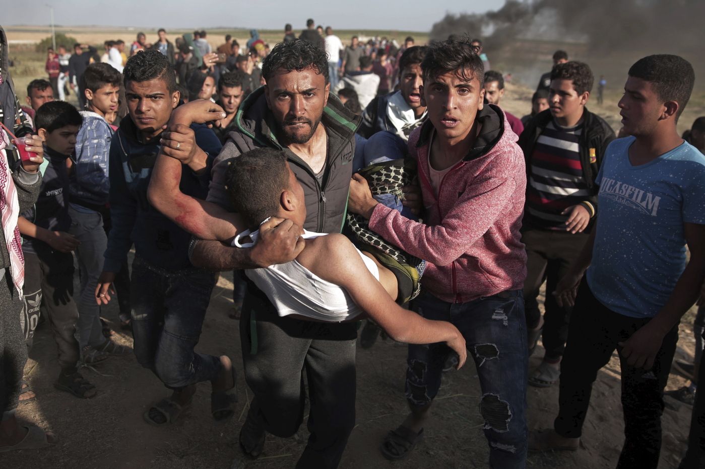 Palestinian protesters carry a wounded man who was shot by Israeli troops during a protest near the Gaza Strip border with Israel, in eastern Gaza City, Saturday, March 31, 2018. (AP Photo/ Khalil Hamra)