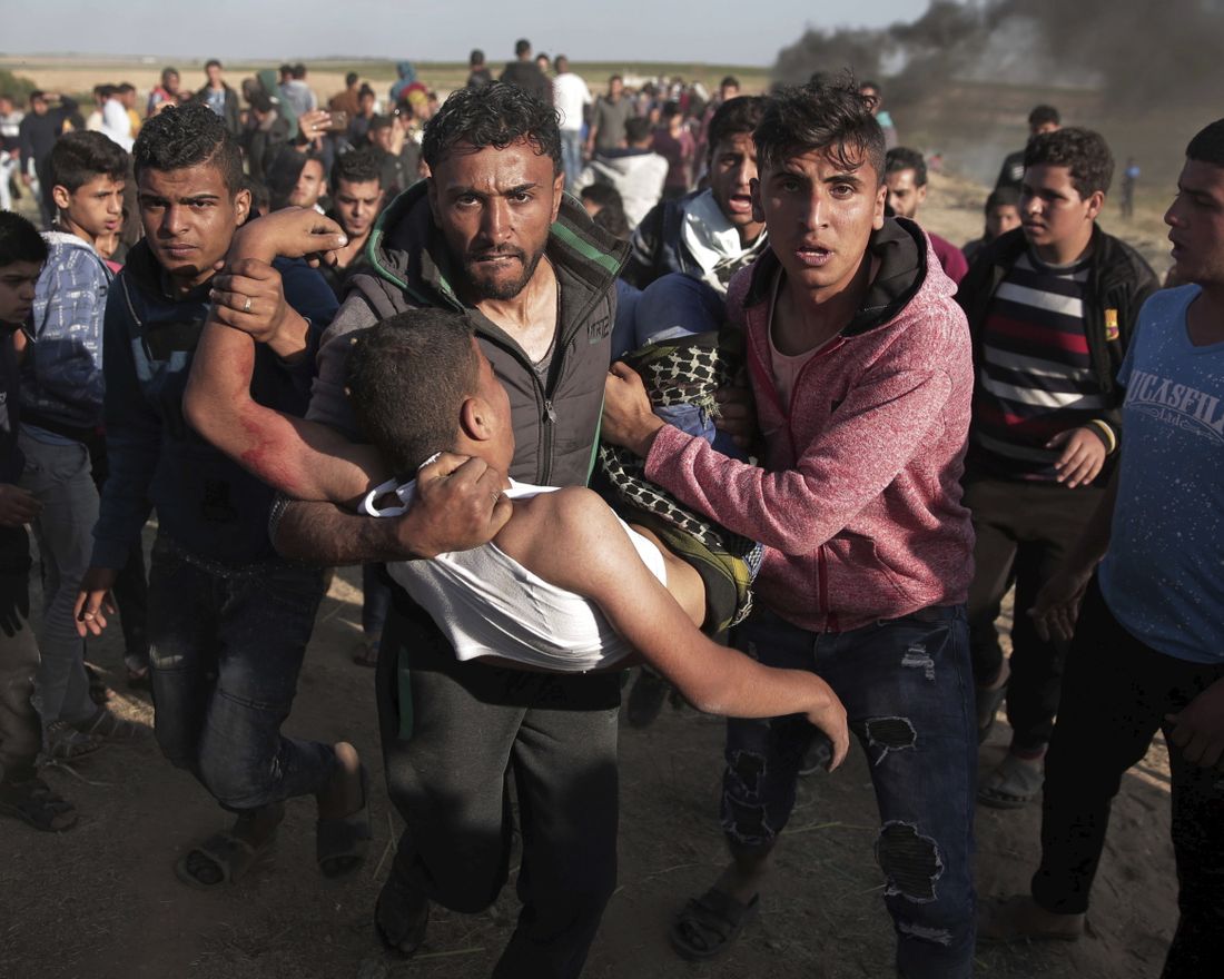 Palestinian protesters carry a wounded man who was shot by Israeli troops during a protest near the Gaza Strip border with Israel, in eastern Gaza City, Saturday, March 31, 2018. (AP Photo/ Khalil Hamra)