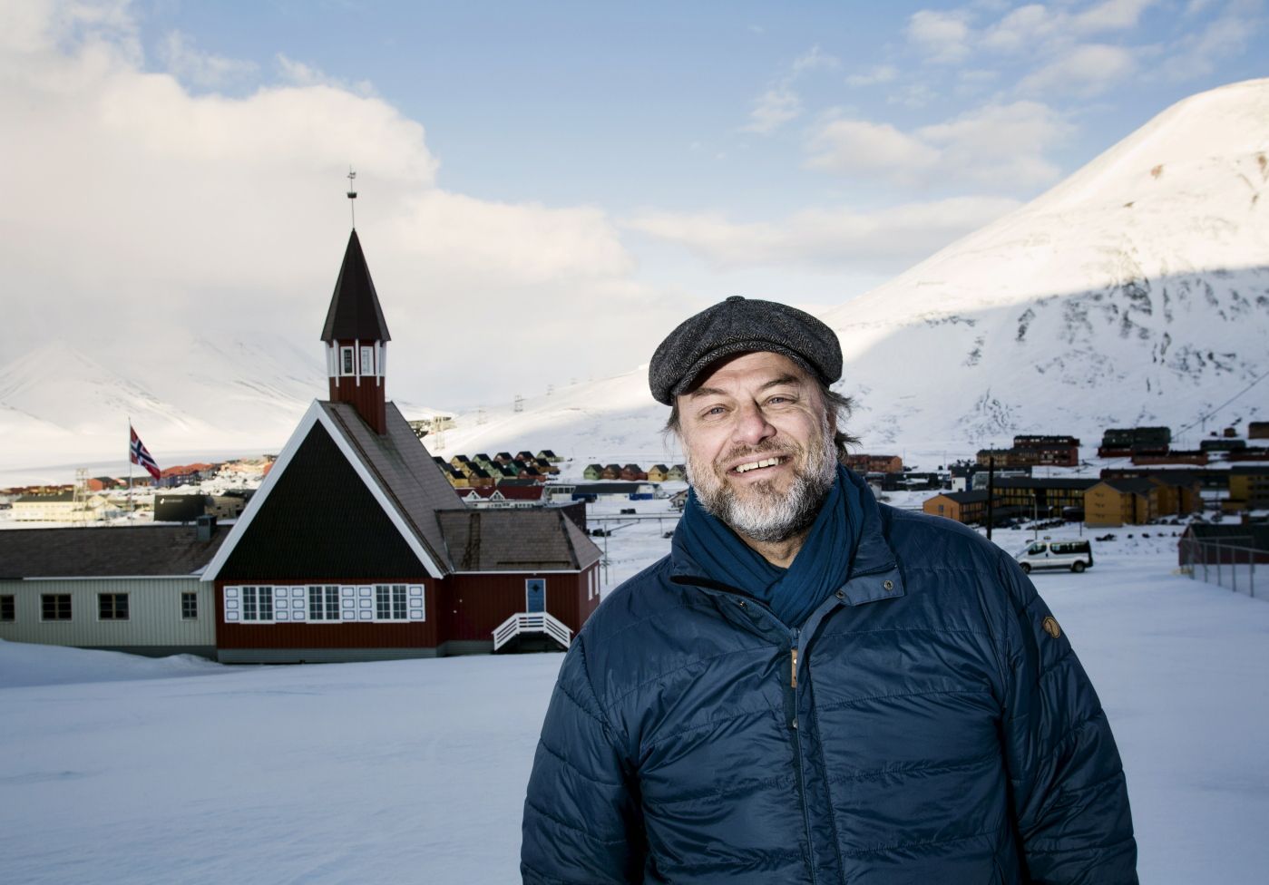 Leif Magne Helgesen, sogneprest på Svalbard, med Svalbard kirke og Longyerabyen i bakgrunnen.