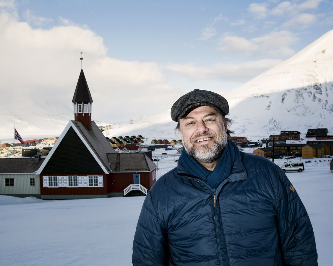 Leif Magne Helgesen, sogneprest på Svalbard, med Svalbard kirke og Longyerabyen i bakgrunnen.