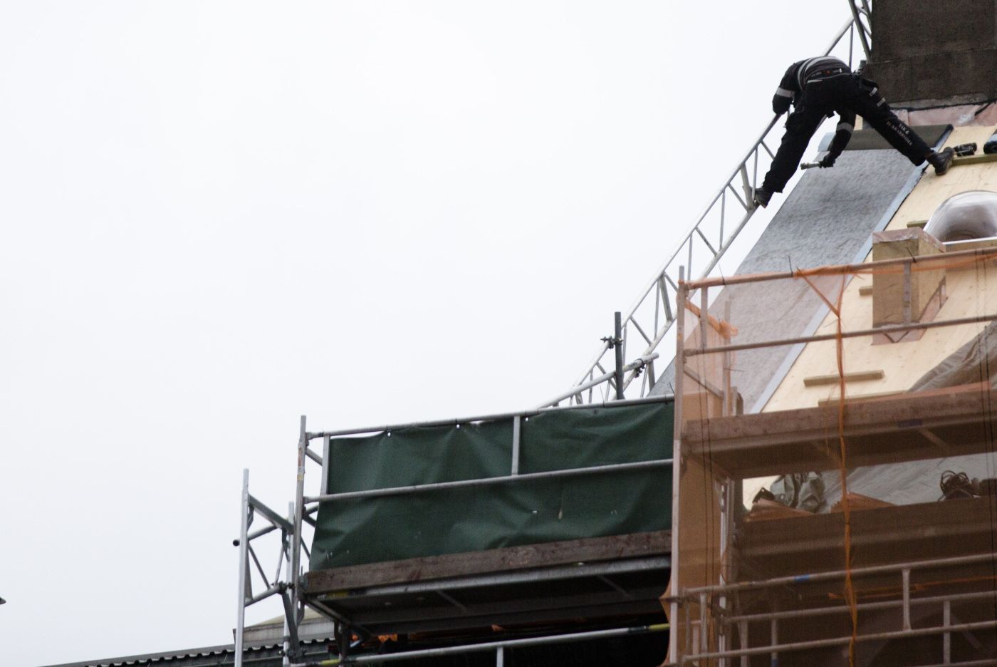 En mann legger kobber på et tak i Oslo sentrum, uten sikring. Arbeidsmiljø, byggebransjen, håndverk, taktekker, taktekking, stillas. 
  
 Foto: Tom Henning Bratlie/Klassekampen