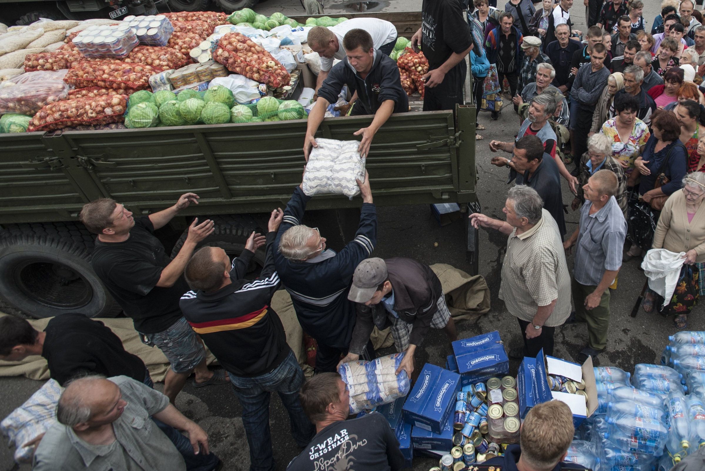 FILE - Local residents receive food stuff as humanitarian aid in a central square in Slovyansk, eastern Ukraine, Sunday, July 6, 2014. The eastern Ukrainian city of Slovyansk was occupied by pro-Russian separatists for months in 2014. Now its people are preparing to defend their community again as the fighting draws closer and invites a major battle. Slovyansk is a city of splintered loyalties, with some residents antagonistic toward Kyiv or nostalgic for their Soviet past. (AP Photo/Evgeniy Maloletka, File)