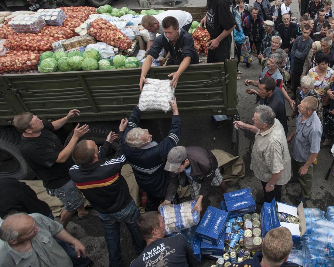 FILE - Local residents receive food stuff as humanitarian aid in a central square in Slovyansk, eastern Ukraine, Sunday, July 6, 2014. The eastern Ukrainian city of Slovyansk was occupied by pro-Russian separatists for months in 2014. Now its people are preparing to defend their community again as the fighting draws closer and invites a major battle. Slovyansk is a city of splintered loyalties, with some residents antagonistic toward Kyiv or nostalgic for their Soviet past. (AP Photo/Evgeniy Maloletka, File)
