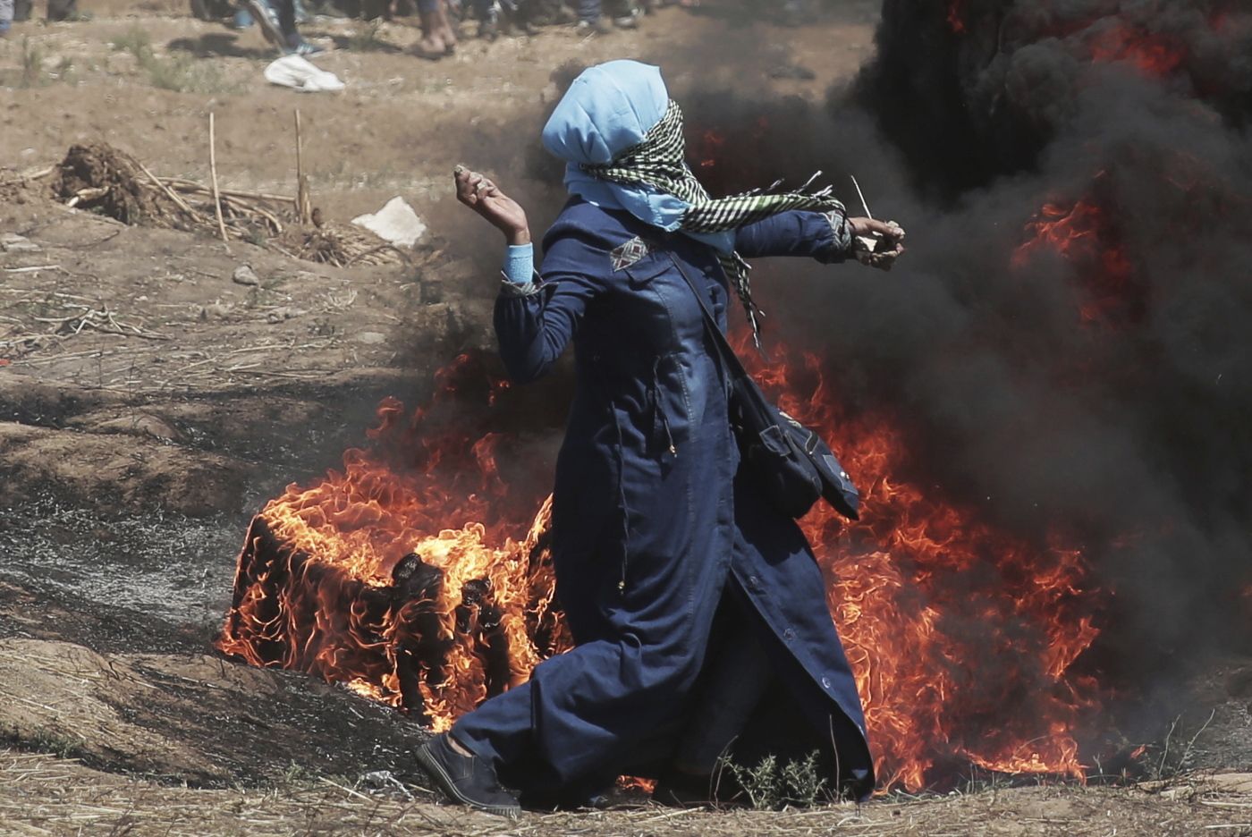 A Palestinian woman hurls stones towards Israeli troops during a protest at the Gaza Strip's border with Israel, Monday, May 14, 2018. Israeli fire has killed dozens of Palestinians during mass protests along the Gaza border, marking the deadliest day of violence since a devastating 2014 cross-border war and casting a pall over Israel's festive inauguration of the new U.S. Embassy in contested Jerusalem. (AP Photo/Khalil Hamra)