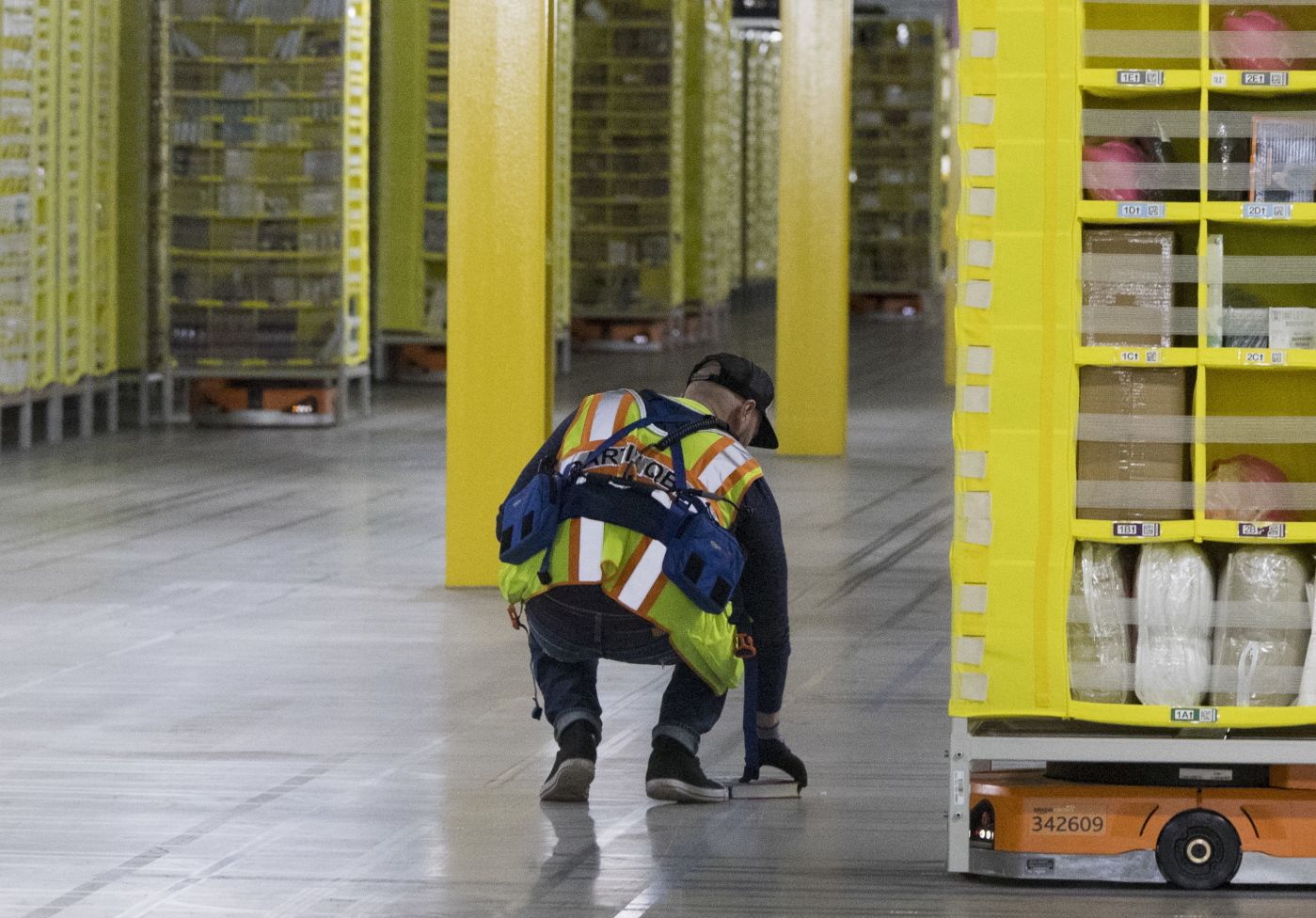 In this Dec. 5, 2018, Amazon Amnesty Quarterback Artur Yilnaz retrieves a book that fell off a pod at the Amazon fulfillment center on Staten Island borough of New York. Robots aren?ƒÙt replacing everyone, but a quarter of U.S. jobs will be severely disrupted as artificial intelligence accelerates the automation of today?ƒÙs work, according to a new Brookings Institution report published Thursday, Jan. 24, 2019. (AP Photo/Mary Altaffer)
