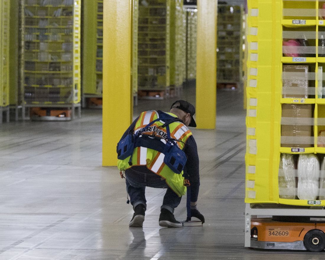 In this Dec. 5, 2018, Amazon Amnesty Quarterback Artur Yilnaz retrieves a book that fell off a pod at the Amazon fulfillment center on Staten Island borough of New York. Robots aren?ƒÙt replacing everyone, but a quarter of U.S. jobs will be severely disrupted as artificial intelligence accelerates the automation of today?ƒÙs work, according to a new Brookings Institution report published Thursday, Jan. 24, 2019. (AP Photo/Mary Altaffer)