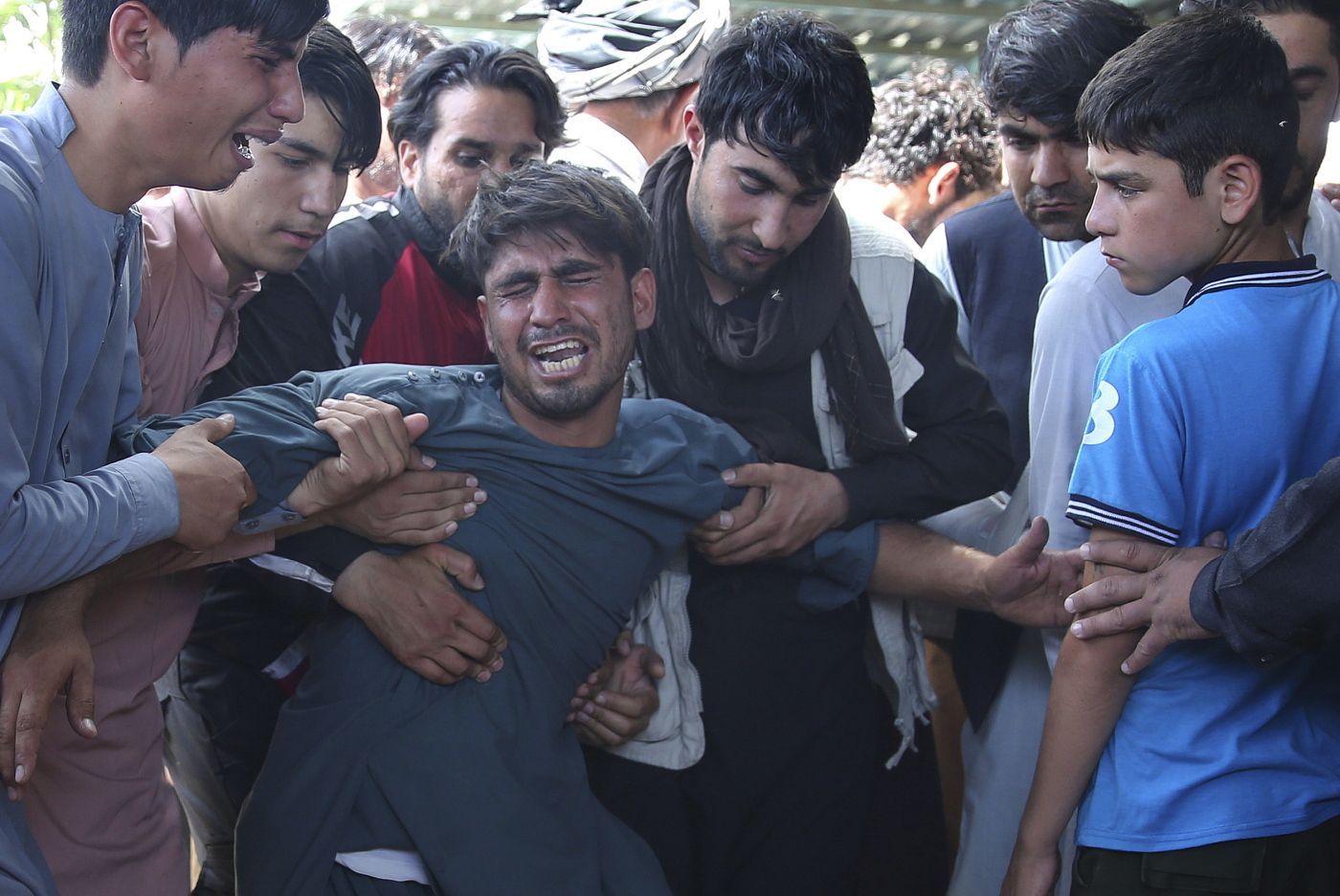 Relatives grieve near the coffins of victims of the Dubai City wedding hall bombing during a mass funeral in Kabul, Afghanistan, Sunday, Aug.18, 2019. The deadly bombing at the wedding in Afghanistan's capital late Saturday that killed dozens of people was a stark reminder that the war-weary country faces daily threats not only from the long-established Taliban but also from a brutal local affiliate of the Islamic State group, which claimed responsibility for the attack. (AP Photo/Rafiq Maqbool)