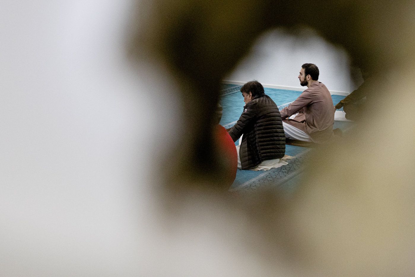 Feiring av eid i Al-Noor-moskeen i Bærum, mai 2020. Et av skuddene under  terrorangrepet 10. august 2019 etterlot seg et stort hull i veggen mellom bønnerommet og gangen. De fleste av moskeens medlemmer har holdt seg unna forsamlingshuset etter terrorangrepet. Etter korona-nedstengningen i mars 2020 har moskeen vært stengt, som alle andre steder. I forkant av eid-feiringen ga myndighetene tillatelse til åpning av større forsamlingshus, med begrenset antall deltakere. Al-Noor åpnet for tre eid-bønner, med forhåndsregistrering av dem som skulle delta. Mellom hver bønn, ble lokalene desinfisert. 
  
 Foto: Tom Henning Bratlie