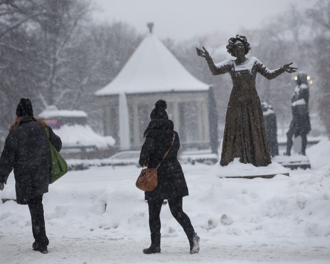 Svarte vinterklær vinter snø Karl Johans gate i Oslo, ved Nationalteathret og statuen av Wenche Foss.