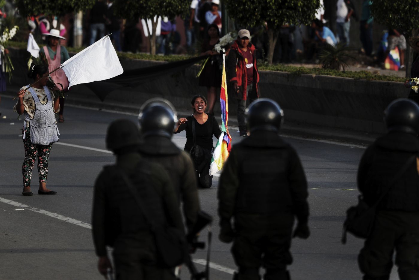A coca leaf producer kneels leads with police to open the way so a march by backers of former President Evo Morales may continue to Cochabamba, Bolivia, Saturday, Nov. 16, 2019. Officials now say at least eight people died when Bolivian security forces fired on Morales supporters the day before, in Sacaba. The U.N. human rights chief says she's worried that Bolivia could "spin out of control" as the interim government tries to restore stability following the resignation of the former president in an election dispute. (AP Photo/Juan Karita)