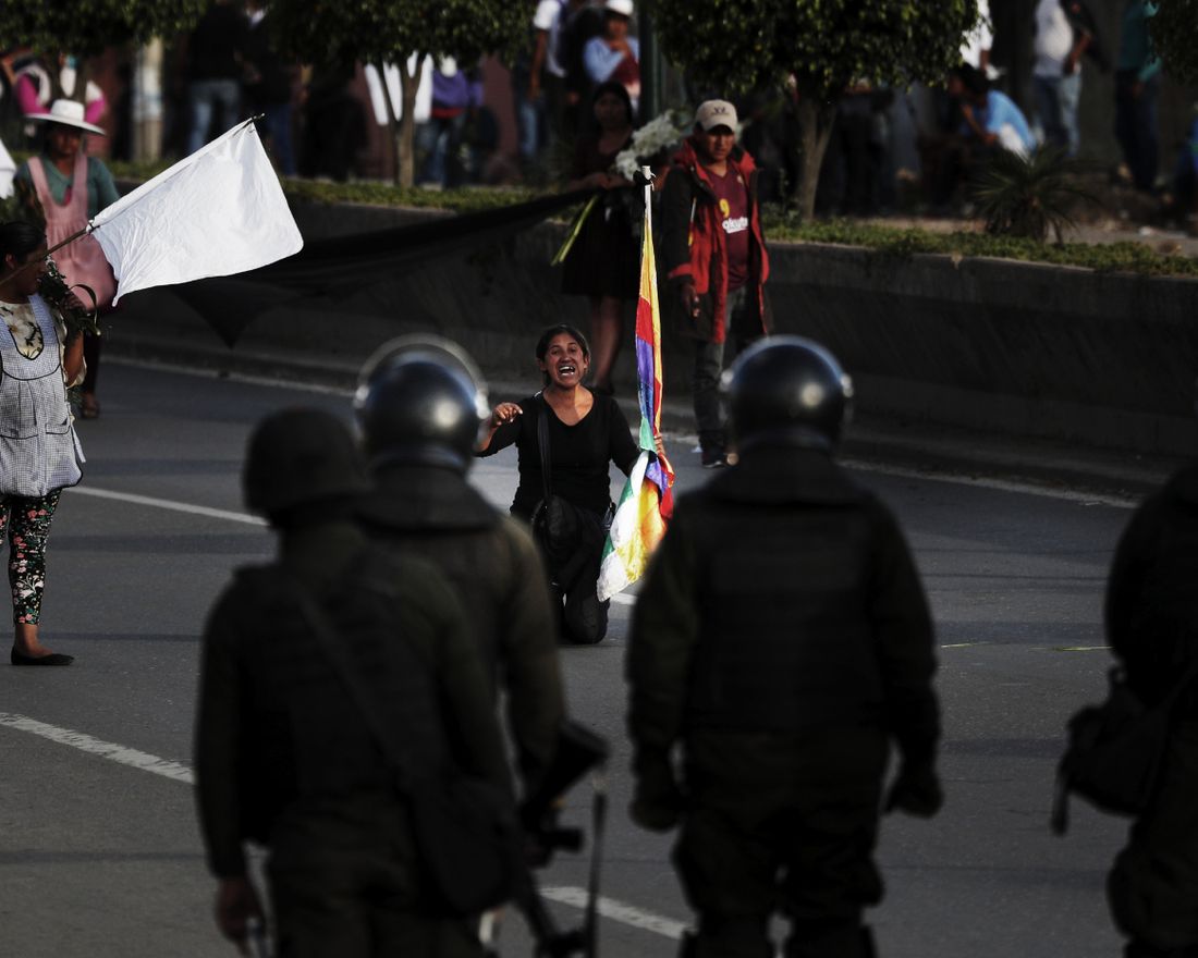 A coca leaf producer kneels leads with police to open the way so a march by backers of former President Evo Morales may continue to Cochabamba, Bolivia, Saturday, Nov. 16, 2019. Officials now say at least eight people died when Bolivian security forces fired on Morales supporters the day before, in Sacaba. The U.N. human rights chief says she's worried that Bolivia could "spin out of control" as the interim government tries to restore stability following the resignation of the former president in an election dispute. (AP Photo/Juan Karita)