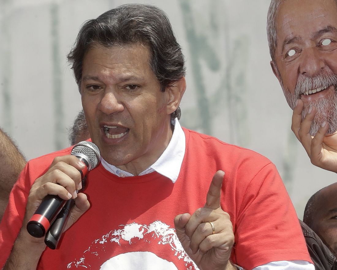 Brazil's presidential candidate for the Workers Party Fernando Haddad speaks to supporters 
 during a campaign rally in Carapicuiba, the greater Sao Paulo area, Brazil, Thursday, Sept. 13, 2018. At right is a mask of jailed, former president Luiz Inacio Lula da Silva, who Haddad replaces as the party's candidate ahead of Oct. 7 elections. (AP Photo/Andre Penner)