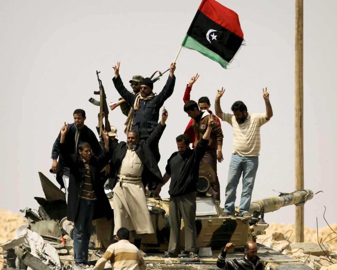TOPSHOTS 
 Libyan rebels celebrate on a pro-Kadhafi forces destroyed tank as they enter the strategic oil town of Ajdabiya after defensive positions previously held by loyalists stood deserted following Western-led air strikes on March 26, 2011.    AFP PHOTO/ PATRICK BAZ