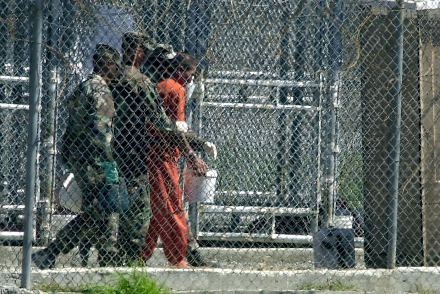 (FILES) A detainee is walked by three US Army MPs to the portable restroom with a bucket from his caged cell 02 March 2002 at Camp X-Ray in Guantanamo Bay, Cuba. Fifty-two prisoners have launched a hunger strike at the US Guantanamo Bay terror suspects camp, 21 July 2005, apparently in protest at their detention, military authorities said.            AFP PHOTO/Peter MUHLY