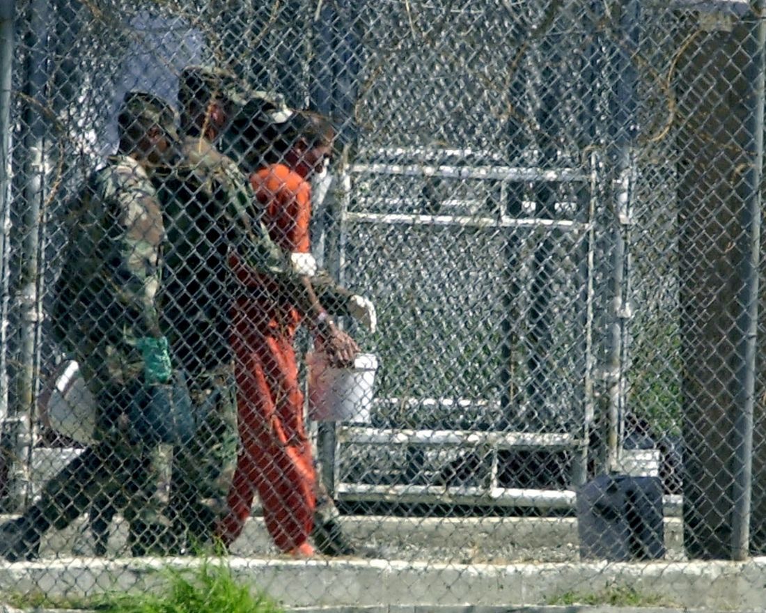 (FILES) A detainee is walked by three US Army MPs to the portable restroom with a bucket from his caged cell 02 March 2002 at Camp X-Ray in Guantanamo Bay, Cuba. Fifty-two prisoners have launched a hunger strike at the US Guantanamo Bay terror suspects camp, 21 July 2005, apparently in protest at their detention, military authorities said.            AFP PHOTO/Peter MUHLY
