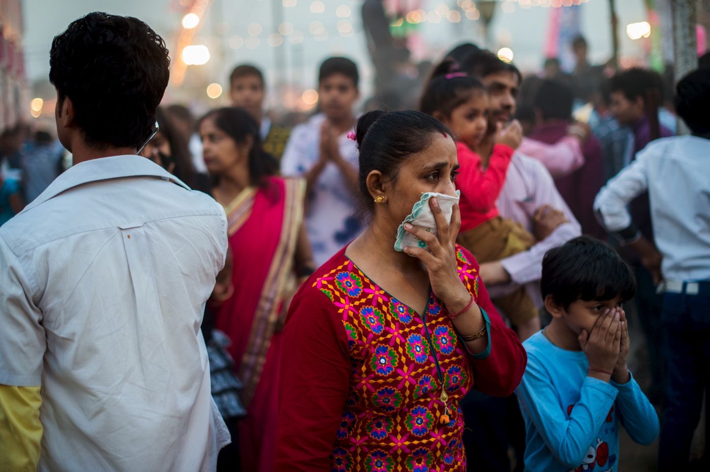 To go with Climate-warming-UN-COP21-India,FOCUS by Trudy Harris 
 In this October 22, 2015 photo, an Indian woman and a child cover their faces in an effort not to breath the fumes from fireworks and heavy dust while walking in a crowd at a local fair in New Delhi.  India's capital, with 18 million residents, has the world's most polluted air with six times the amount of small particulate matter (pm2.5) than what is considered safe, according to the World Health Organization (WHO). The air's hazardous amount of pm2.5 can reach deep into the lungs and enter the blood, causing serious long term health effect, with the WHO warning India has the world's highest death rate from chronic respiratory diseases. India, home to 13 of the world's top 20 polluted cities, is also the third largest emitter of greenhouse gases behind the United States and China. In Delhi, the air pollution is due to vehicle traffic including cargo trucks running on low-grade diesel, individual fires that residents burn in winter, crop being burnt by farmers in neighboring states, and construction site dust. Burning coal in power plants is also major contributor that is expected to increase hugely in the coming decades to match electricity needs of the ever-growing city and its booming satellite towns. AFP PHOTO / ROBERTO SCHMIDT
