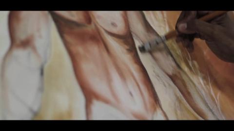 Mão pintando detalhes em um quadro artístico.