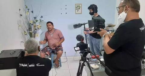 Filmagem interna com pessoa sentada sendo entrevistada.