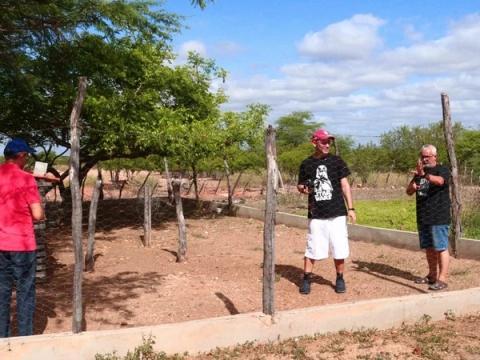 Grupo conversando em área rural cercada por árvores.
