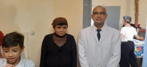 Três pessoas posando juntas: um homem em terno branco, uma mulher com lenço na cabeça e um menino ao lado.