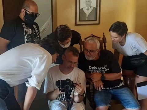 Pessoas reunidas em sala observando câmera.