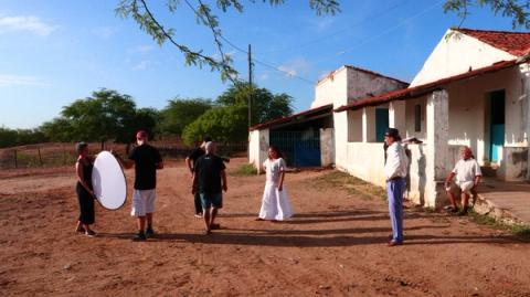 Equipe de filmagem ao ar livre, com mulher segurando difusor de luz.