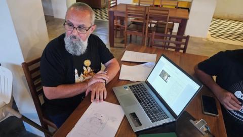 Diretor em mesa de madeira com laptop e desenhos de storyboard.