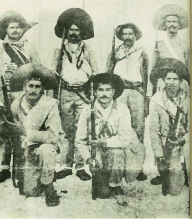 Grupo de cangaceiros com roupas tradicionais e chapéus, posando para foto.