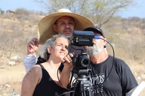 Câmera sendo operada por três pessoas em cenário externo.