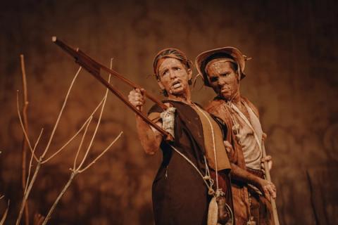 Dois atores com maquiagem teatral, um deles segurando uma muleta.