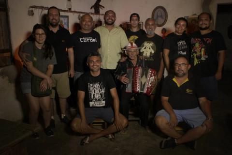 Grupo posando dentro de casa, com um homem tocando acordeão.
