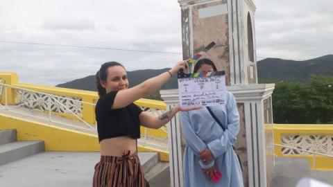 Duas mulheres em altar com vista para montanhas, uma segurando claquete.