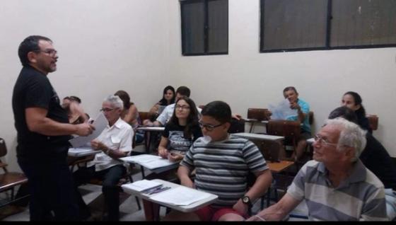 Professor falando para alunos sentados em uma sala de aula.