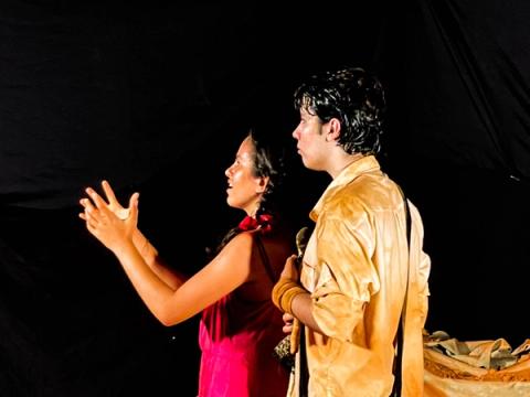 Atriz gestual expressiva ao lado de ator, ambos em cena dramática.