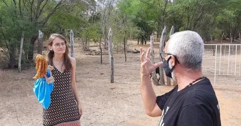 Mulher segurando um boneco e homem fazendo gestos com as mãos.