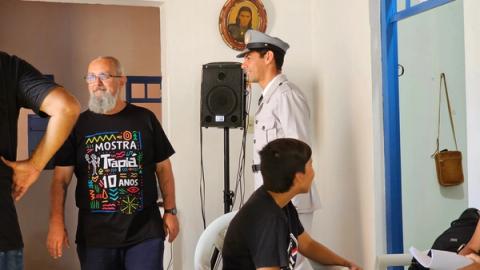 Ator uniformizado e diretor posicionados próximos à caixa de som.